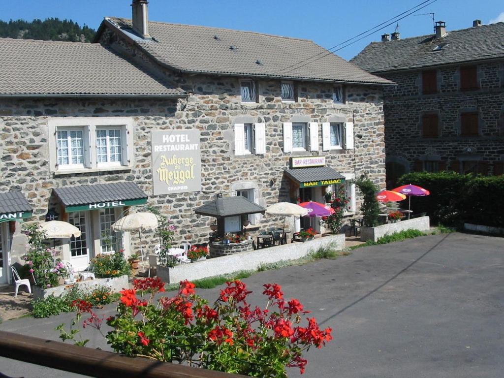 un edificio con sombrillas y flores delante de él en Auberge du Meygal, en Champclause