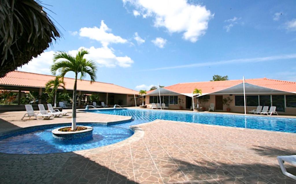 a swimming pool with a palm tree next to a building at Punta Chame Club and Resort in Pajonal