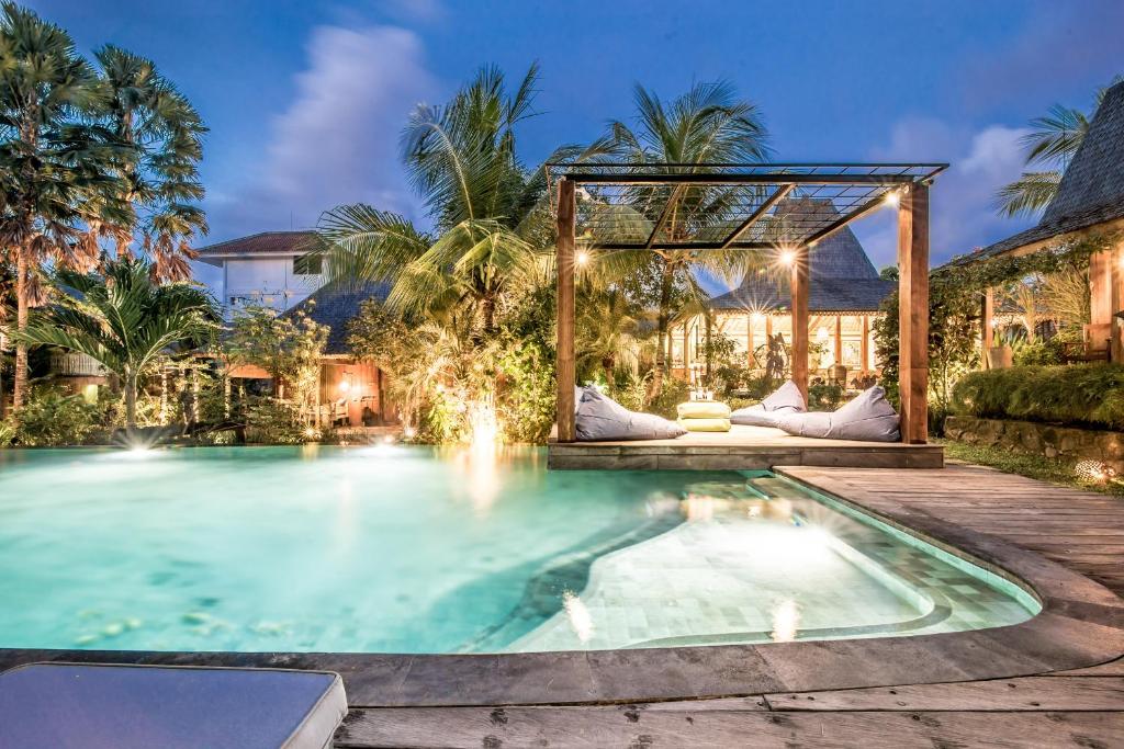 a swimming pool with a pergola next to a house at Wayang Retreat in Canggu