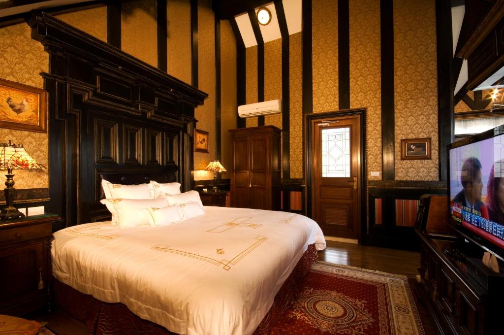 a bedroom with a large bed and a tv at The Old England Manor in Ren&#39;ai