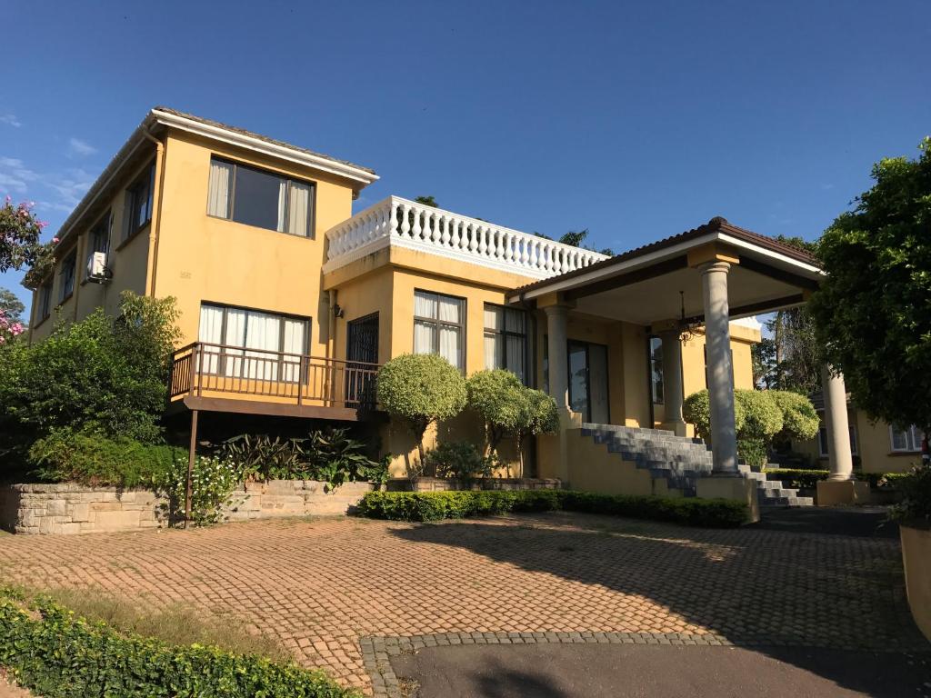 a large yellow house with a brick driveway at Edens Guest House in Durban