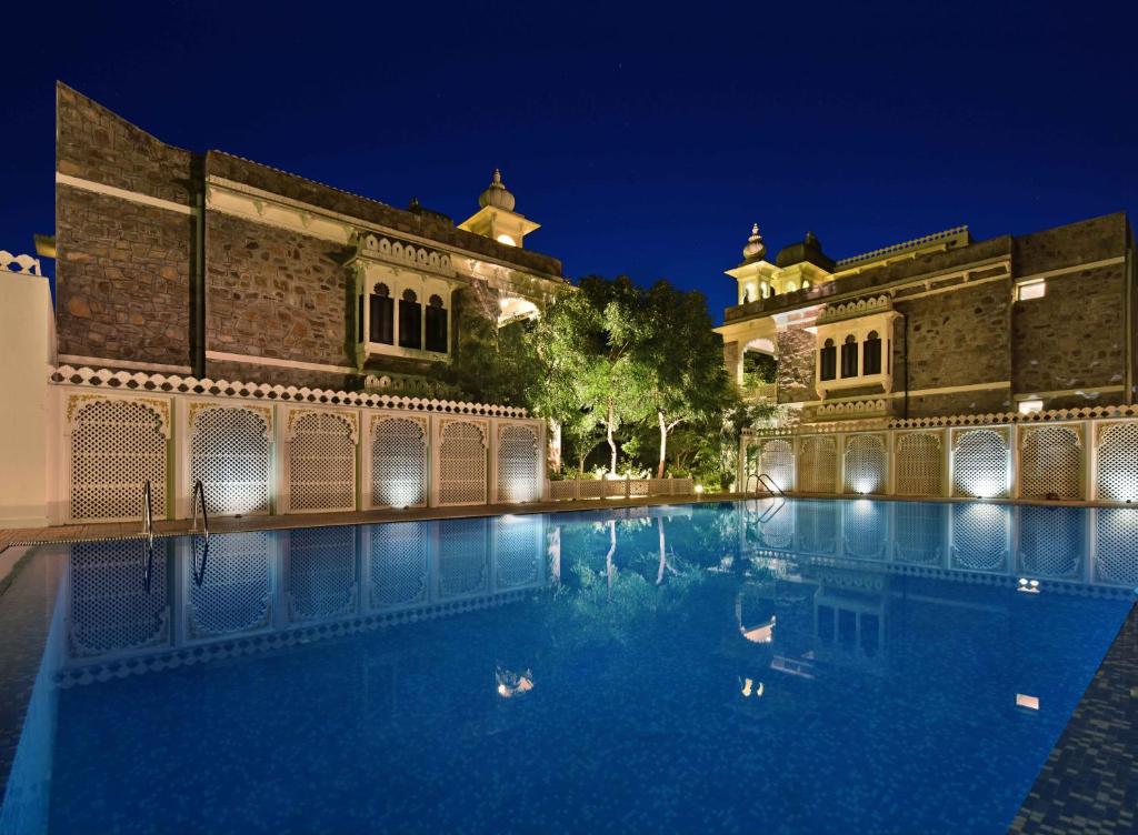 乌代浦乌代巴度假村的夜晚建筑物前的游泳池