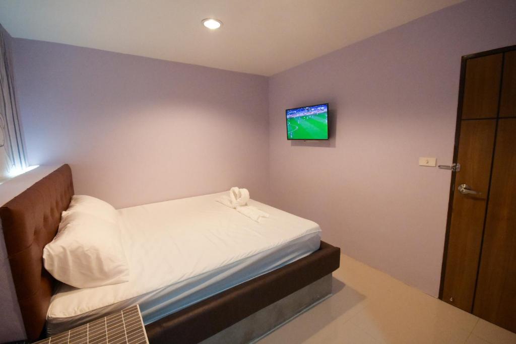 ein kleines Schlafzimmer mit einem Bett und einem TV an der Wand in der Unterkunft Rabbit Room in Bangkok