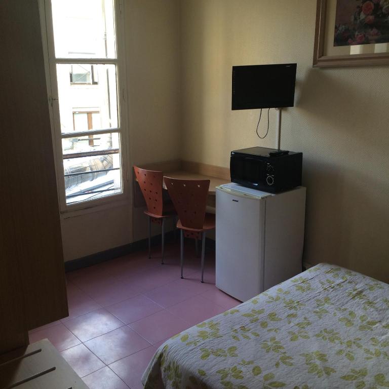 a bedroom with a bed and a desk with a television at Au Royal Mad in Paris