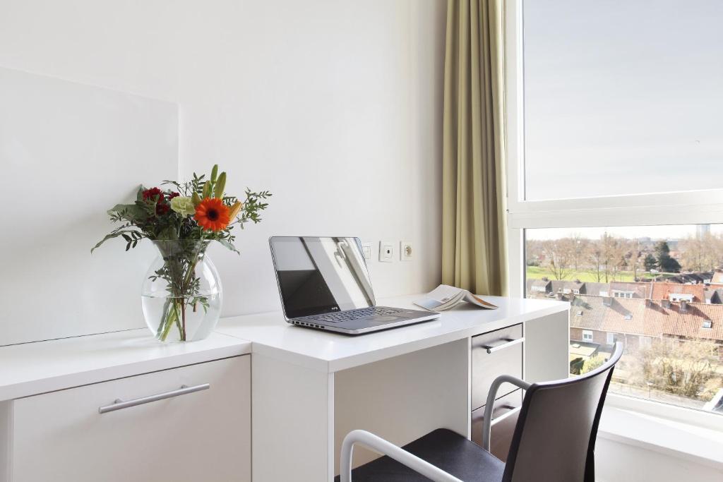 un escritorio blanco con un ordenador portátil y un jarrón de flores en Neoresid - Résidence Lille-Lambret, en Lille