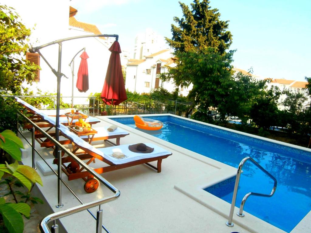 einen Pool mit Stühlen, einem Tisch und einem Sonnenschirm in der Unterkunft Apartments Song in Split