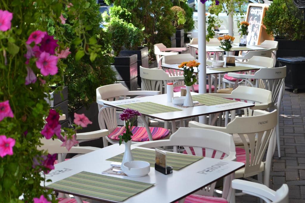 - une rangée de tables et de chaises sur une terrasse fleurie dans l'établissement Hotel Les Jardins Carol, à Bucarest