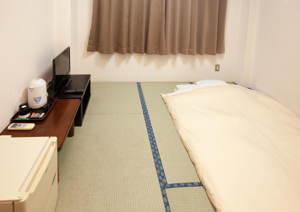 a room with a bed and a desk and a television at Business Hotel Isesaki Heisei Inn in Isesaki