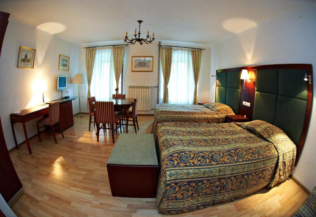 a bedroom with two beds and a table and a desk at Zamek w Dzięgielowie in Dzięgielów