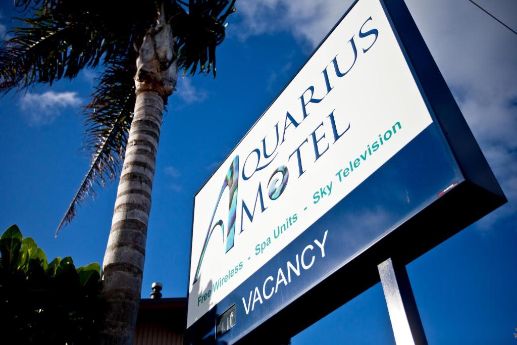 un letrero de la calle frente a una palmera en Aquarius Motel en Ohope Beach