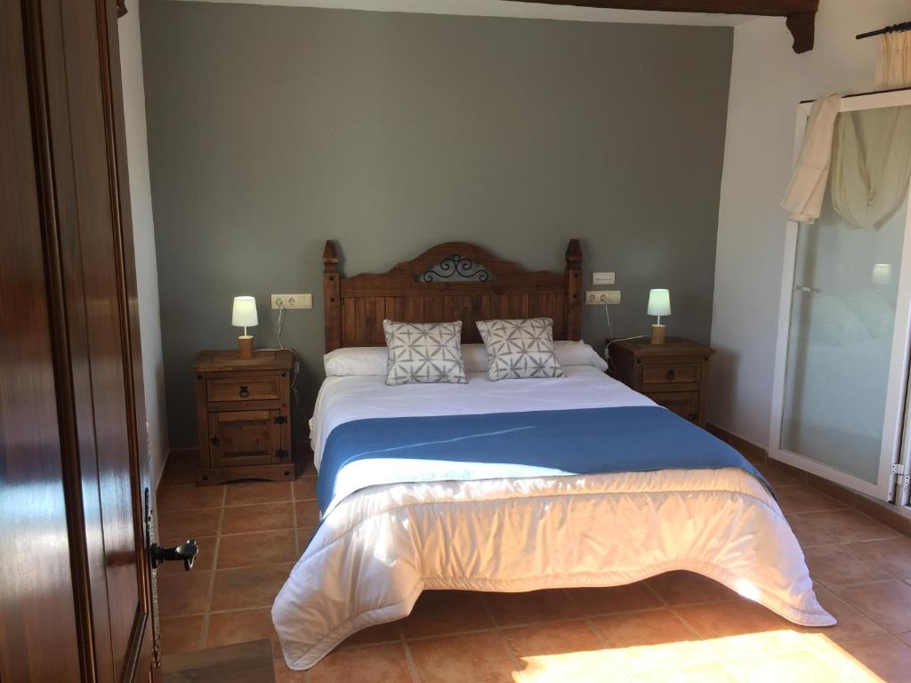 ein Schlafzimmer mit einem großen Bett mit blauer Bettwäsche und Kissen in der Unterkunft Hostal Rural La Casa Verde in Cheles