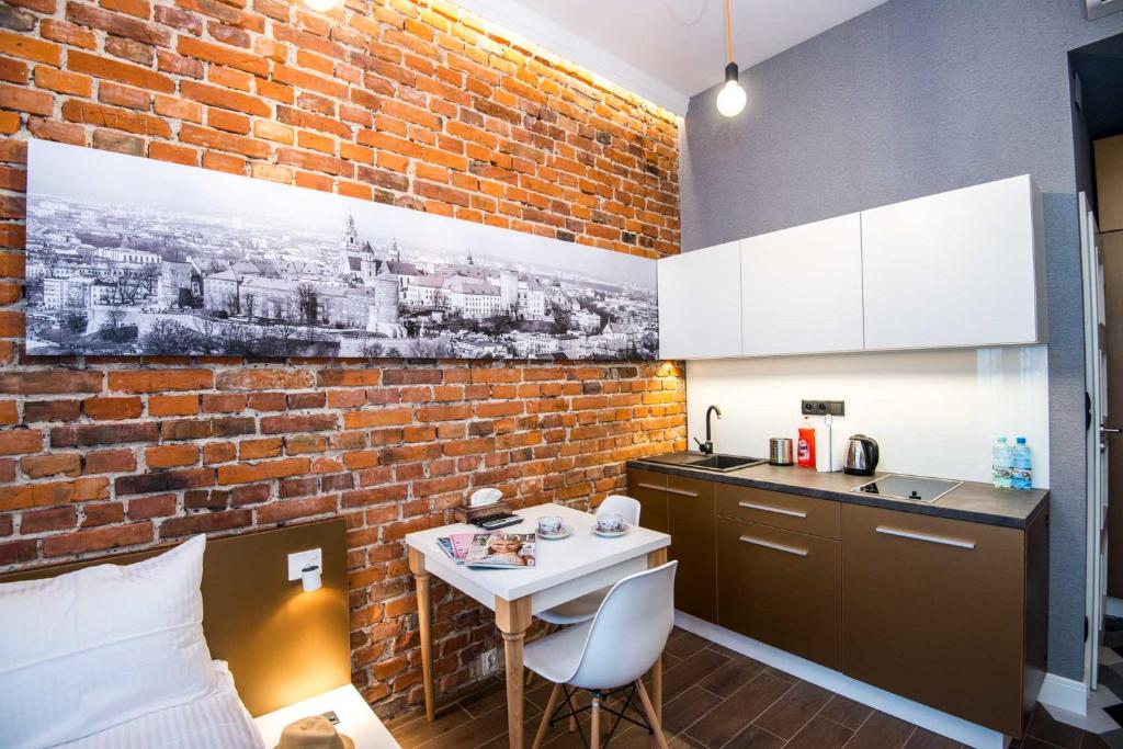 una cucina con muro di mattoni e tavolo in una stanza di Cracow Apartaments II a Cracovia