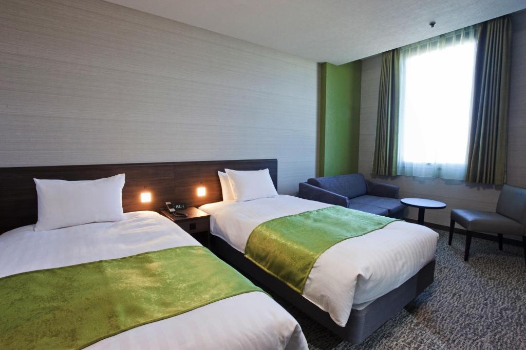 a hotel room with two beds and a couch at Hotel Mielparque Yokohama in Yokohama