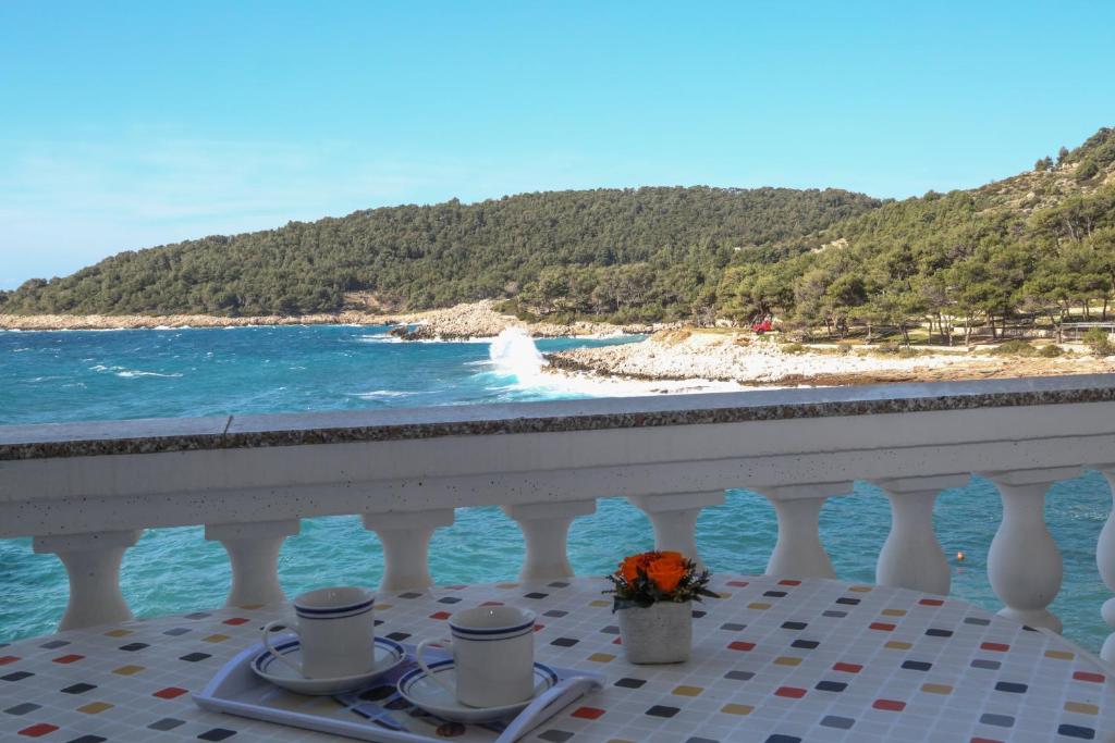 a table with two coffee cups and a view of the ocean at Apartments Dragica in Milna