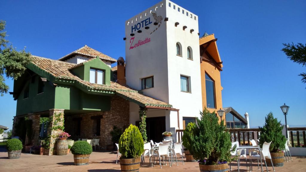 un edificio con mesas y sillas delante de él en Hotel Zerbinetta, en Dílar