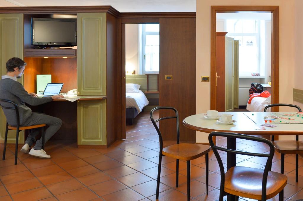 a woman sitting at a table with a laptop in a hotel room at Residence Del Messaggero in Rovereto