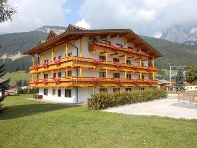 un gran edificio con flores a su lado en Residence Dolomia, en Pozza di Fassa