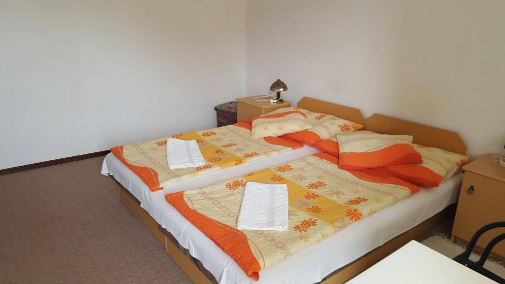 een slaapkamer met een groot bed met oranje en oranje dekens bij Vili Apartmanház in Keszthely