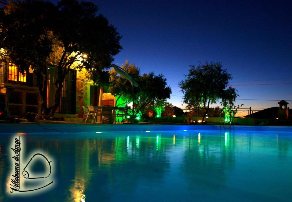 una gran piscina de agua azul con luces verdes en Casa Rural Villabuona Di Amao, en Archidona