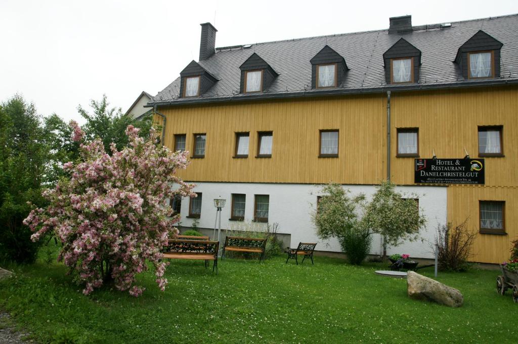 un gran edificio amarillo con un banco y un árbol en Hotel & Restaurant Danelchristelgut, en Lauter