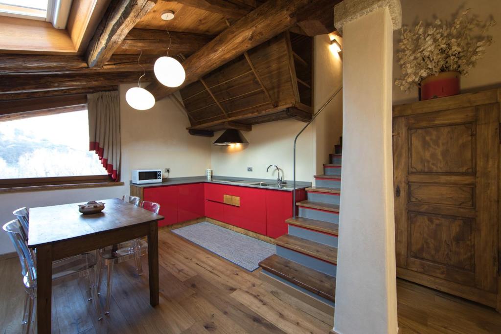 una cocina con armarios rojos, una mesa y una escalera en Maison Lo Triolet en Introd