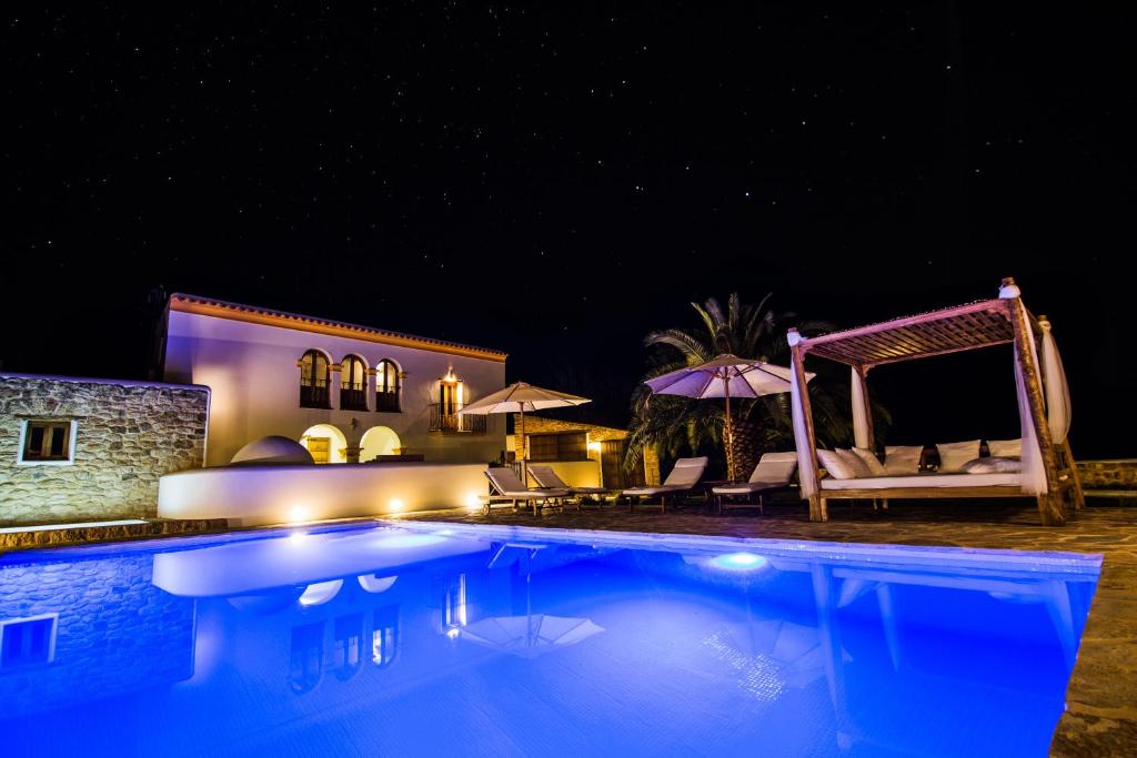 uma piscina à noite com cadeiras e guarda-sóis em Casa Can Pep Cudula em Sant Llorenç de Balafia
