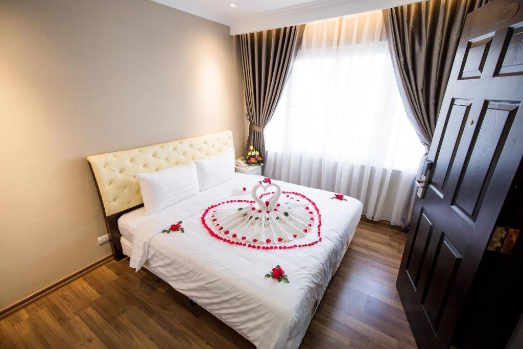 a bedroom with a white bed with a cake on it at Little Hanoi Deluxe Hotel in Hanoi