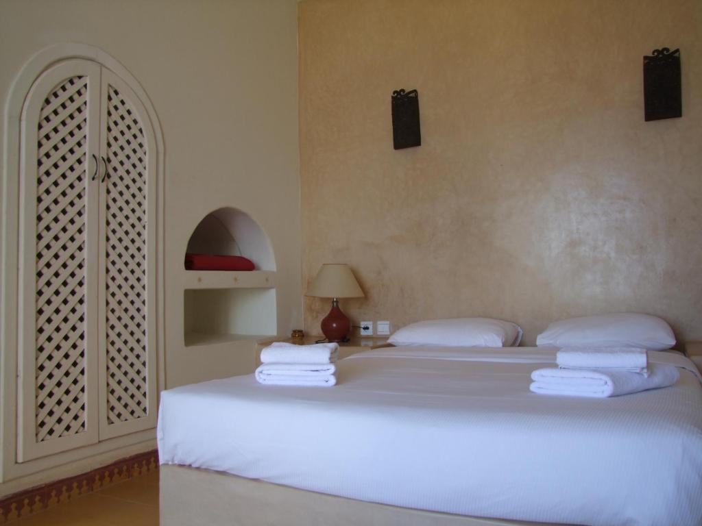 een slaapkamer met een groot wit bed en handdoeken bij Un Thé Au Bout Du Monde in Mirleft