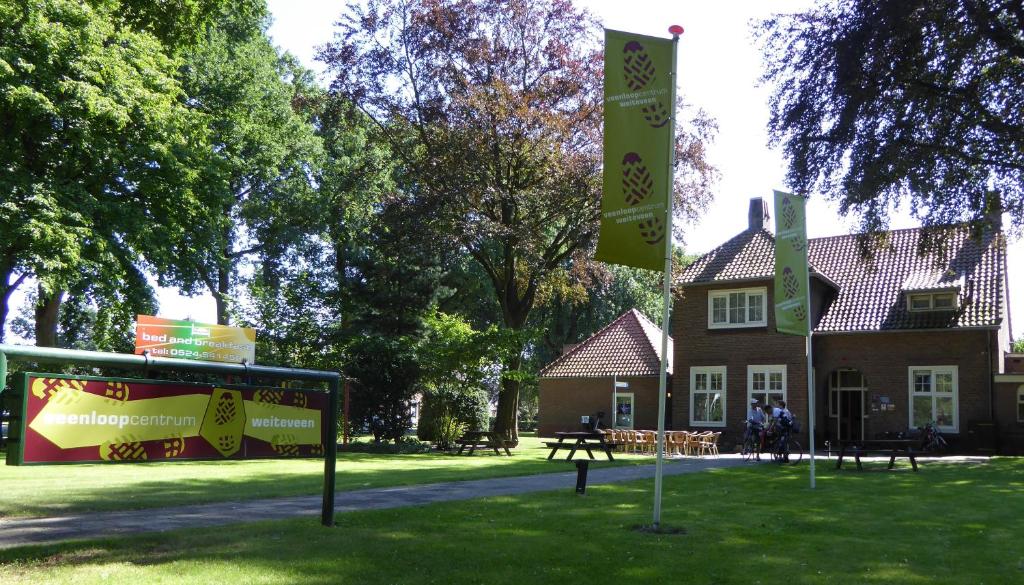 una casa con banderas y un cartel delante de ella en Stichting Veenloopcentrum Weiteveen, en Weiteveen