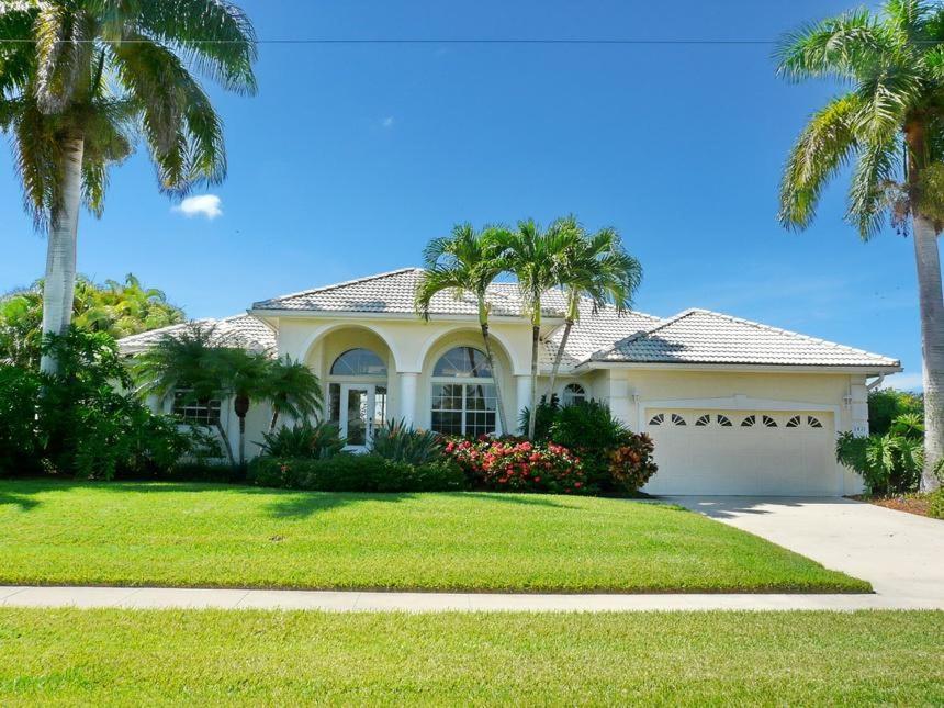 a white house with palm trees in a yard at 1411 Galleon Avenue in Marco Island