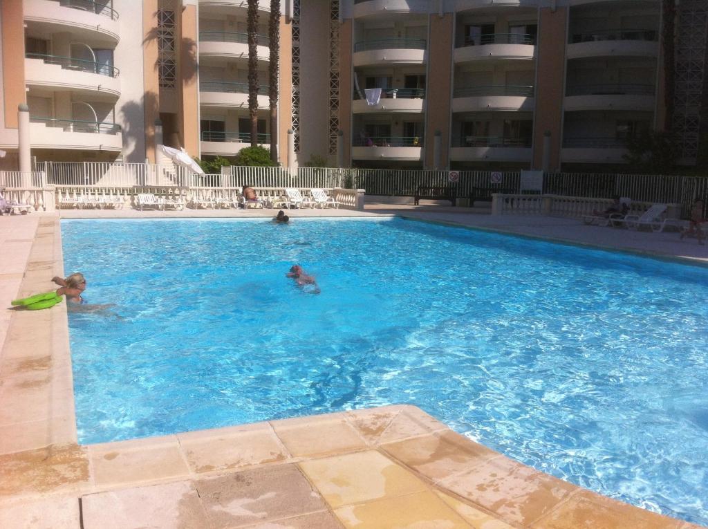 dos personas en una piscina en un edificio en LE CESAREE 3J, en Fréjus