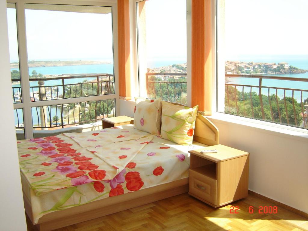 a bedroom with a bed and a balcony with windows at Panoramic Penthouse Sozopol in Sozopol