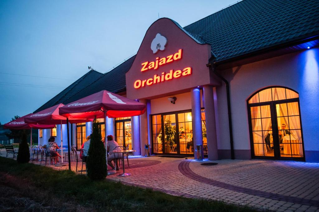 a restaurant with tables and umbrellas in front of it at Zajazd Orchidea - Hotel 24h in Lipsko