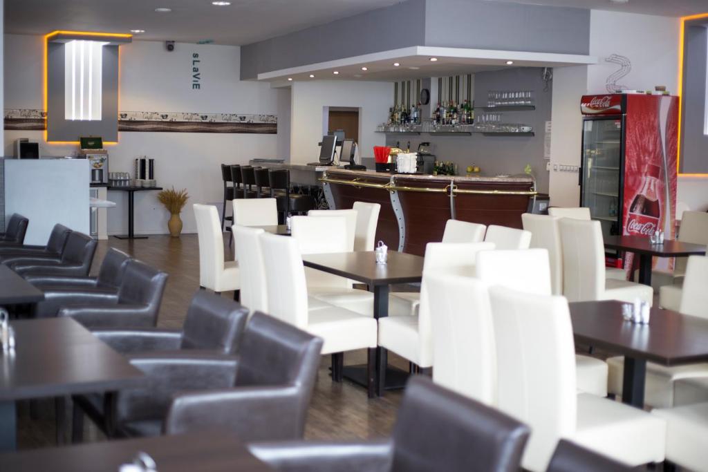 un ristorante con sedie e tavoli bianchi e un bar di Hotel Slavie a Cheb