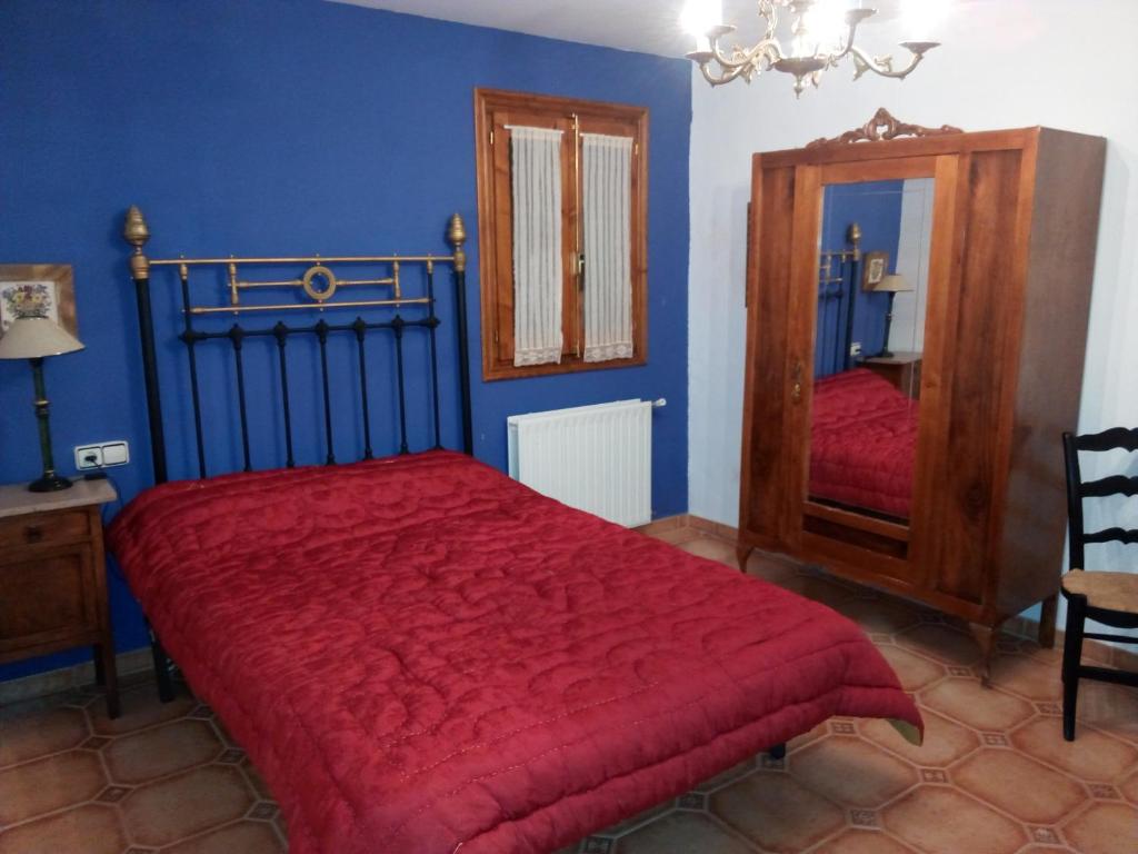 Casa Rural Benede في Chibluco: غرفة نوم بسرير احمر ومرآة