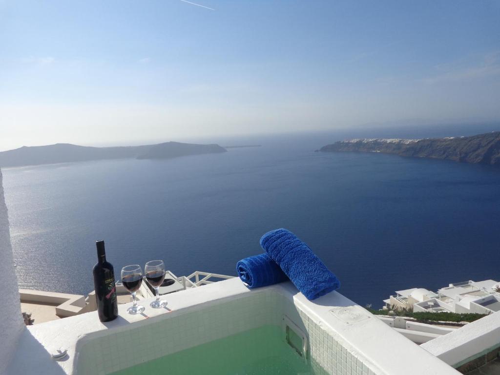 a bottle of wine and glasses sitting on a ledge overlooking the ocean at Langas Villas in Imerovigli