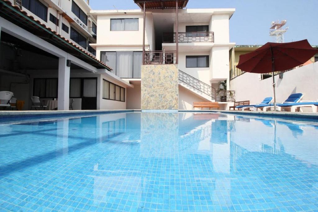 a swimming pool in front of a building with an umbrella at Hotel Sacre in San Juan Bautista Tuxtepec