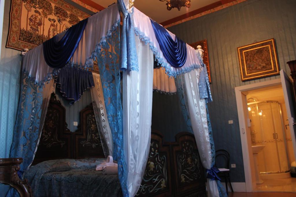 1 dormitorio con cama con dosel y cortinas azules en B&B Domenico Cesarelli en Arena