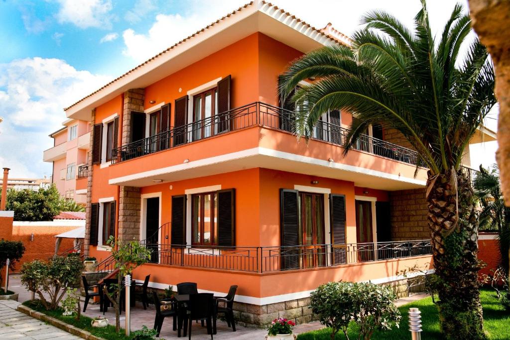 une maison orange avec un palmier en face dans l'établissement Villa Marogna, à Alghero