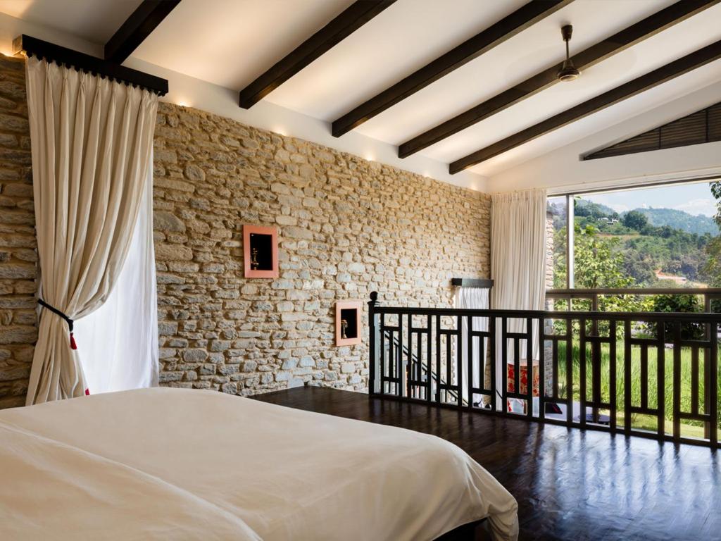 una camera con letto e parete in pietra di The Pavilions Himalayas The Farm a Pokhara