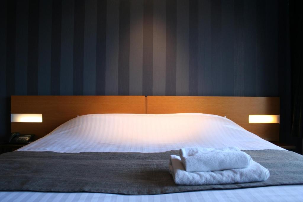 1 dormitorio con 1 cama con 2 toallas en Hotel Sirius en Huy