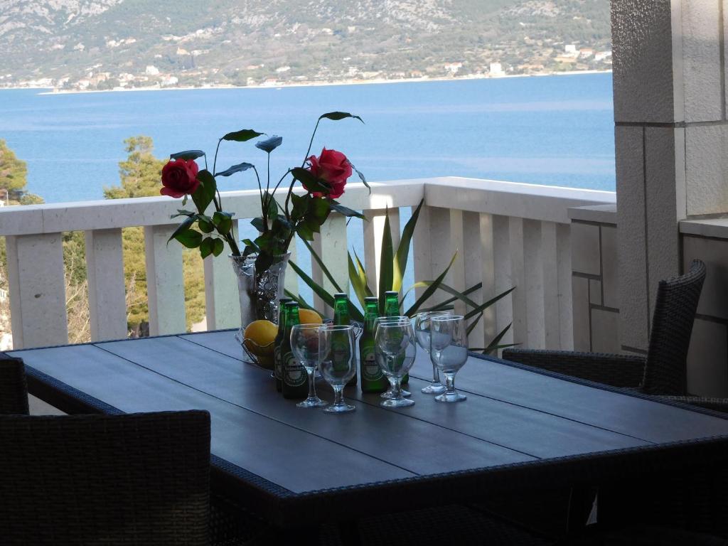 einen blauen Tisch mit Gläsern und Blumen auf dem Balkon in der Unterkunft Apartments Ivancevic in Korčula