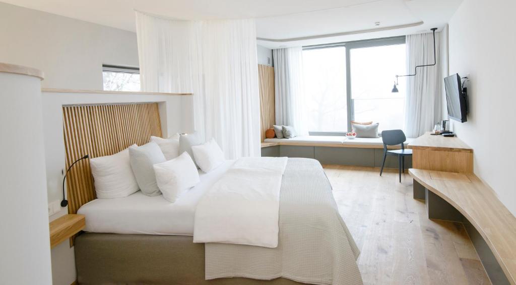 ein weißes Schlafzimmer mit einem Bett und einem Fenster in der Unterkunft Biohotel Mohren in Deggenhausertal