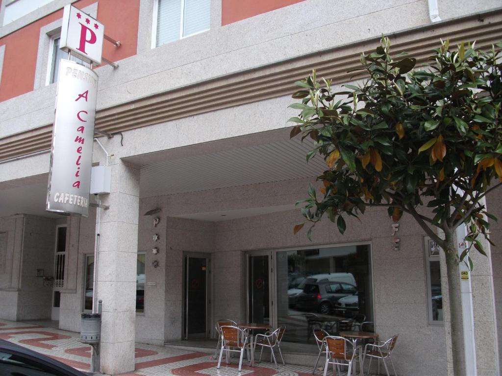 a building with tables and chairs outside of it at Hostal A Camelia in Moaña