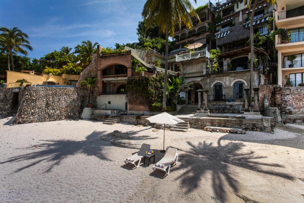 a beach with two chairs and an umbrella and a building at Quinta Maria Cortez in Puerto Vallarta