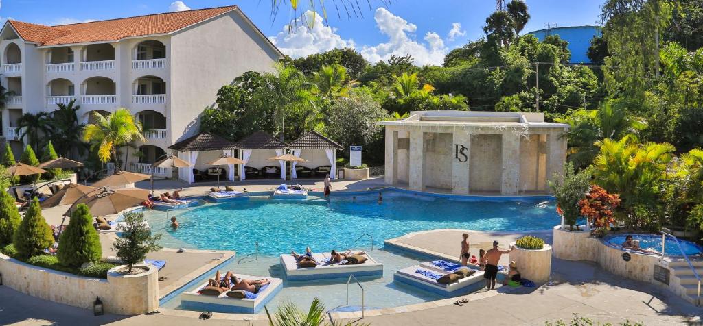 a pool at a resort with people sitting on lounge chairs in it at Presidential Suites by Lifestyle Puerto Plata - All Inclusive in San Felipe de Puerto Plata