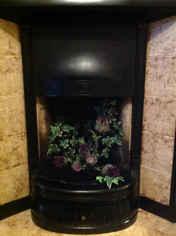 una chimenea con un arreglo floral. en Bed and Breakfast at 4 en Thurso