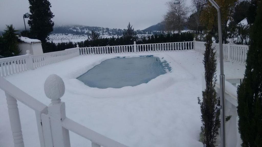 a snow covered yard with a fence and a swimming pool at Casa Rural El Milano in Bullas