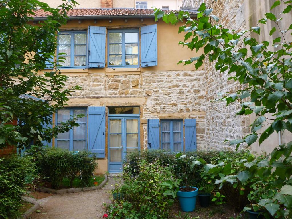 Hotel La marionnette du plateau, an old stone building with blue shutters on it at La marionnette du plateau in Lyon