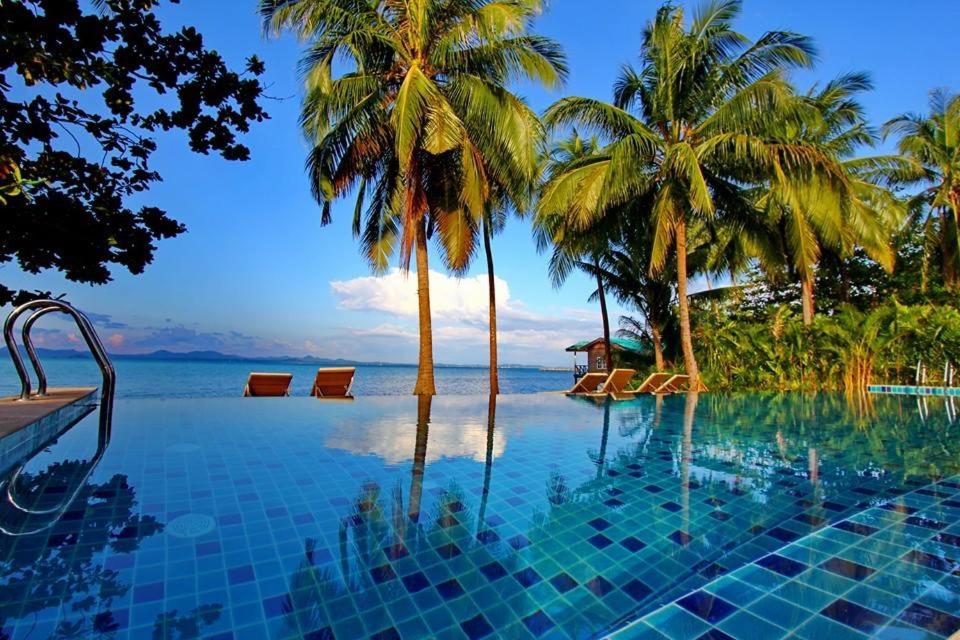 - une piscine bordée de palmiers et une vue sur l'océan dans l'établissement Serenity Resort Koh Chang, à Ko Chang